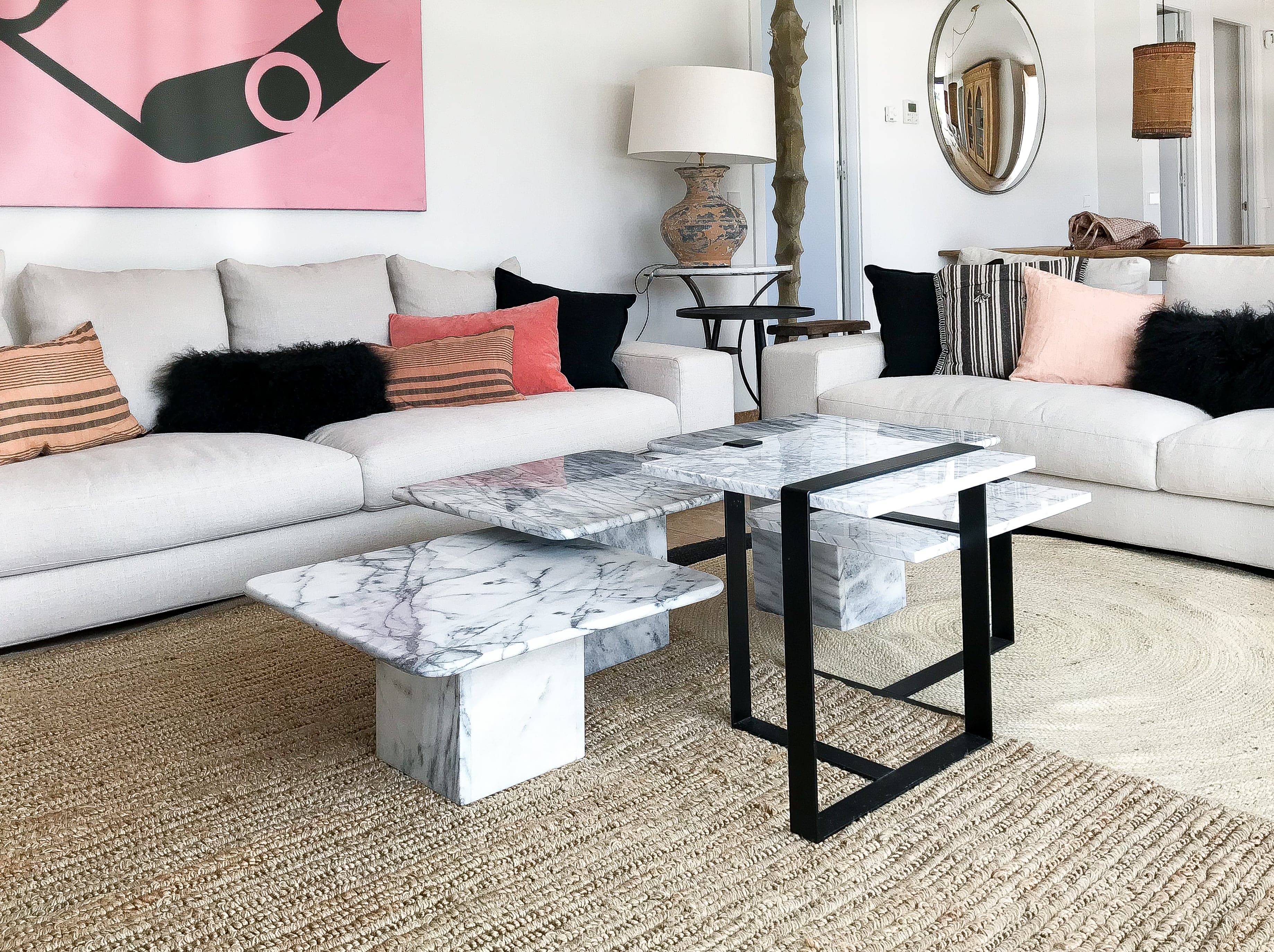Salón con sofás blancos, mesas de mármol y arte rosa y negro
