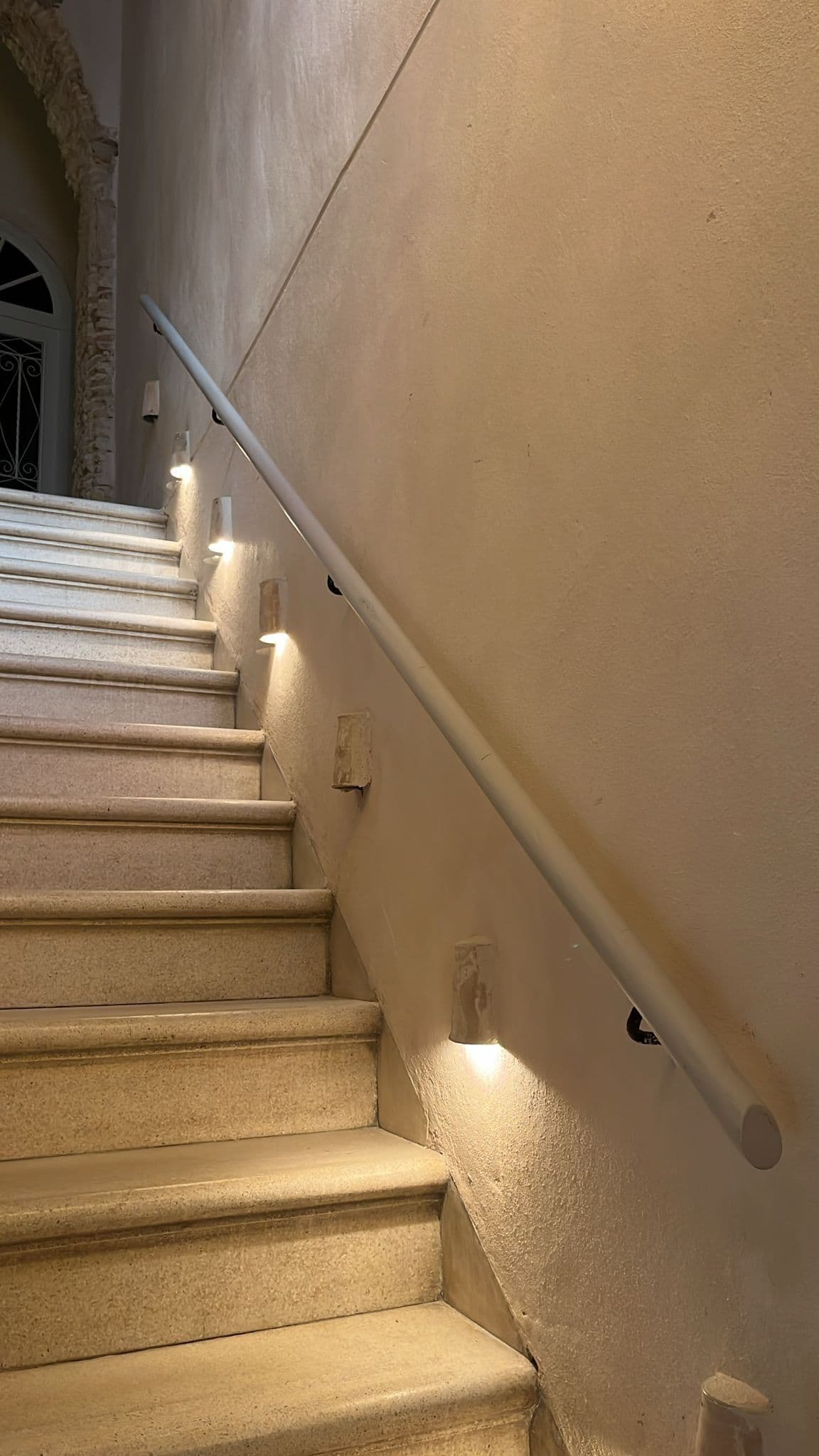Escalera de piedra encalada con pasamanos iluminado