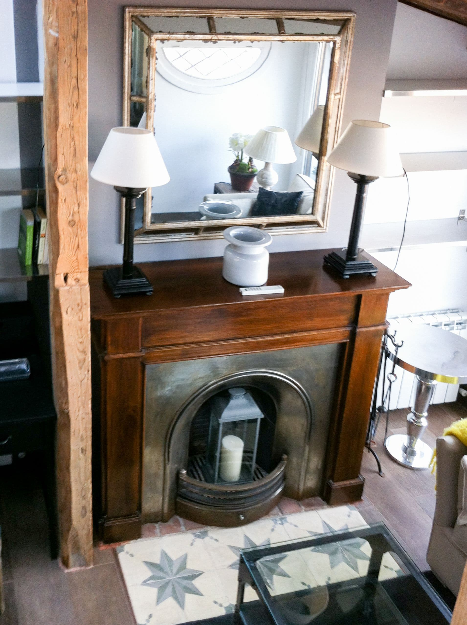 Chimenea antigua de madera con espejo dorado y lámparas gemelas