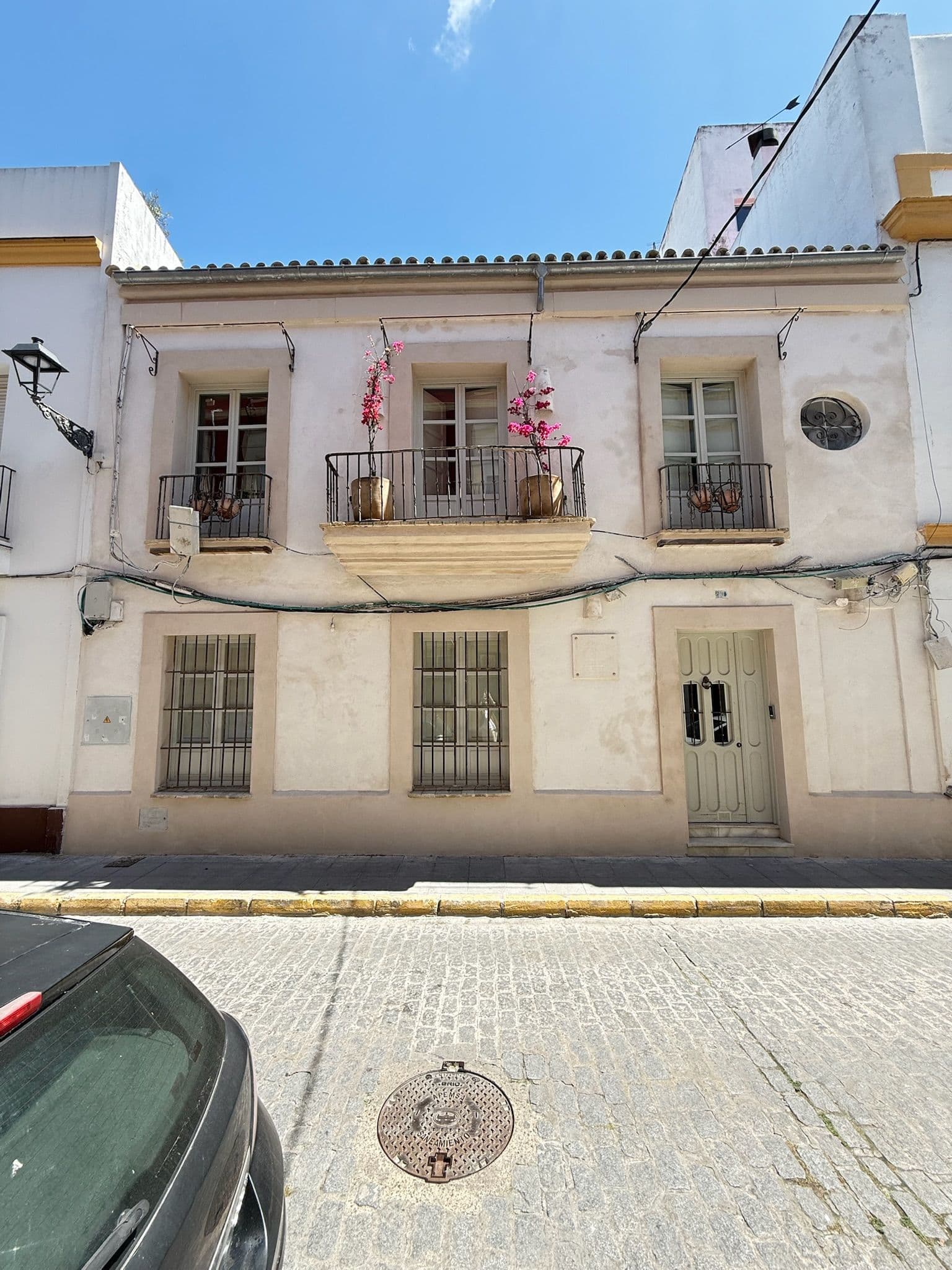 Fachada histórica encalada del edificio, con balcones de forja