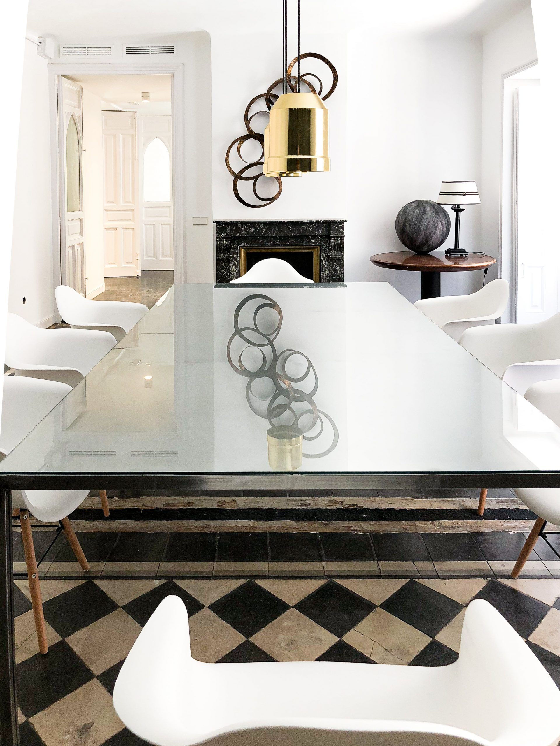 Sala de reuniones con mesa de cristal, sillas blancas y suelo hidráulico ajedrezado original