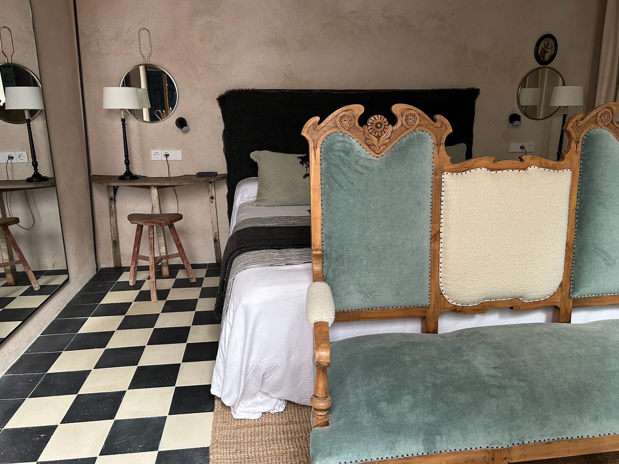 Dormitorio con confidente de terciopelo verde y suelo damero en blanco y negro