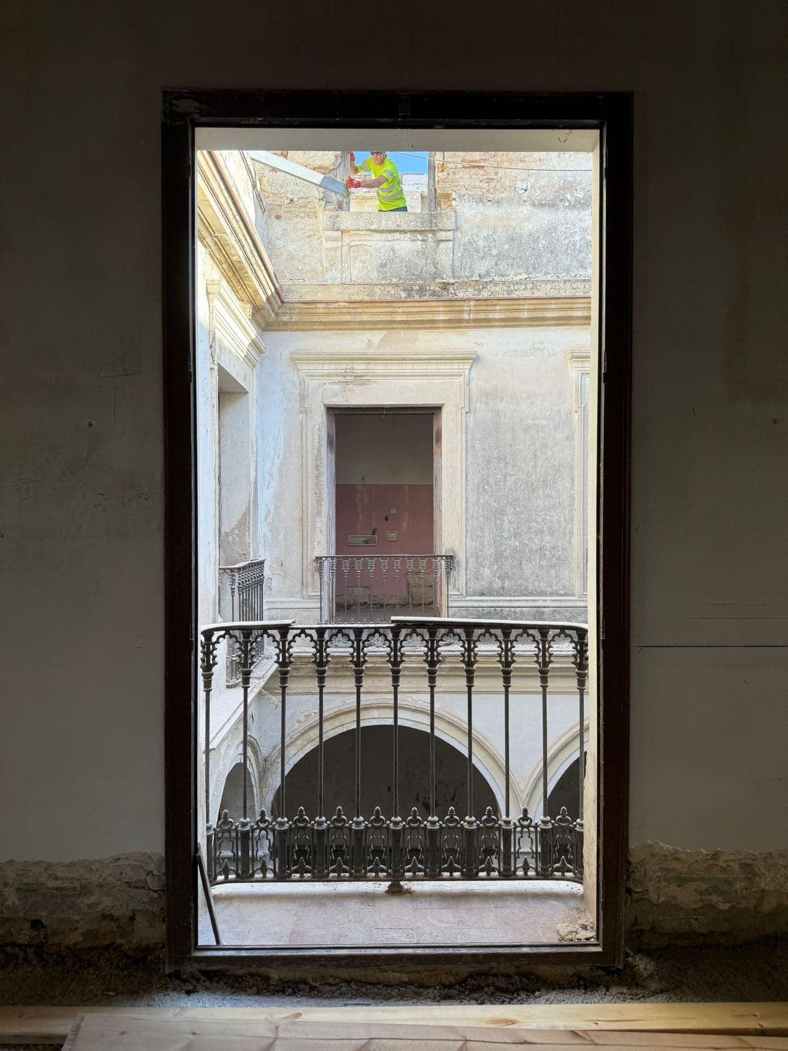 Balcón interior de forja visto a través de una puerta durante la obra