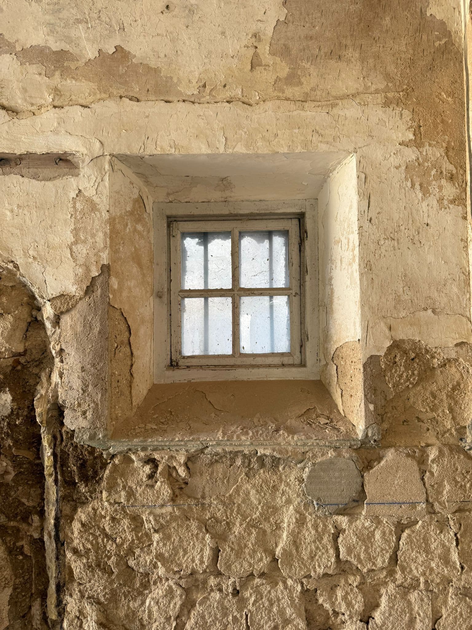 Ventana original de piedra conservada en el muro de mampostería