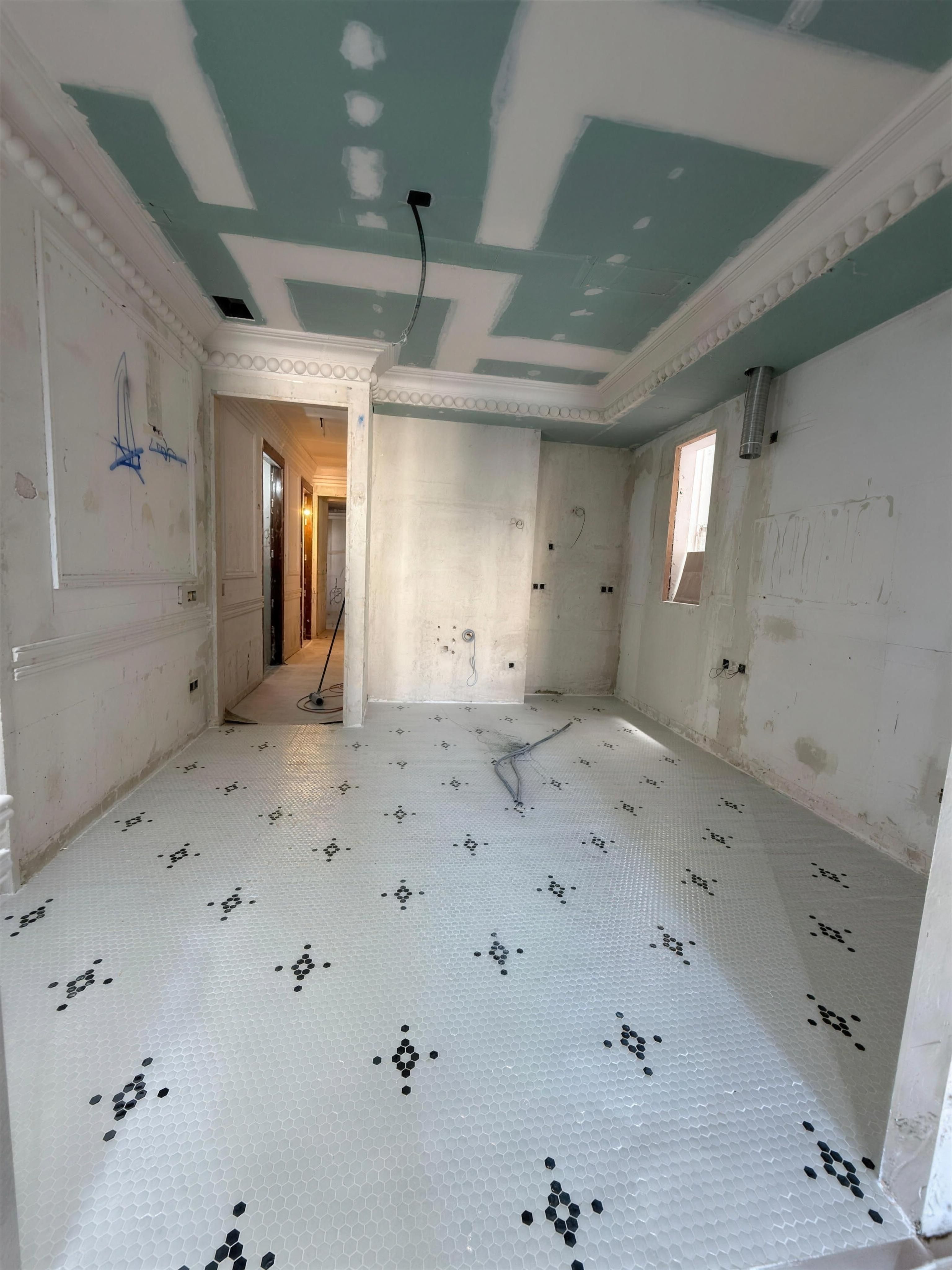 Salón en obras con molduras recuperadas en el techo y pavimento de mosaico original descubierto