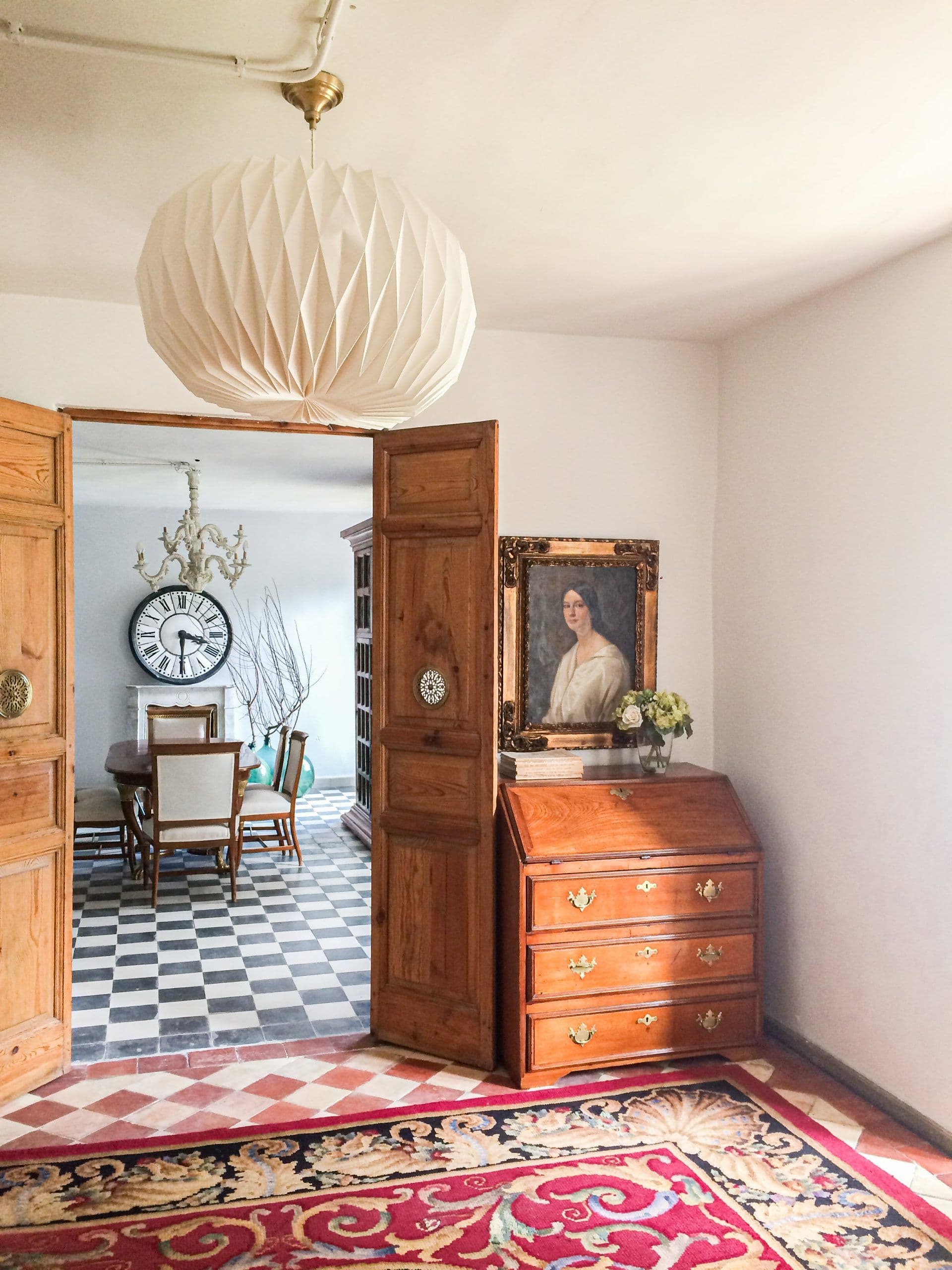 Puerta de madera abierta a la sala del reloj, con escritorio antiguo y alfombra granate