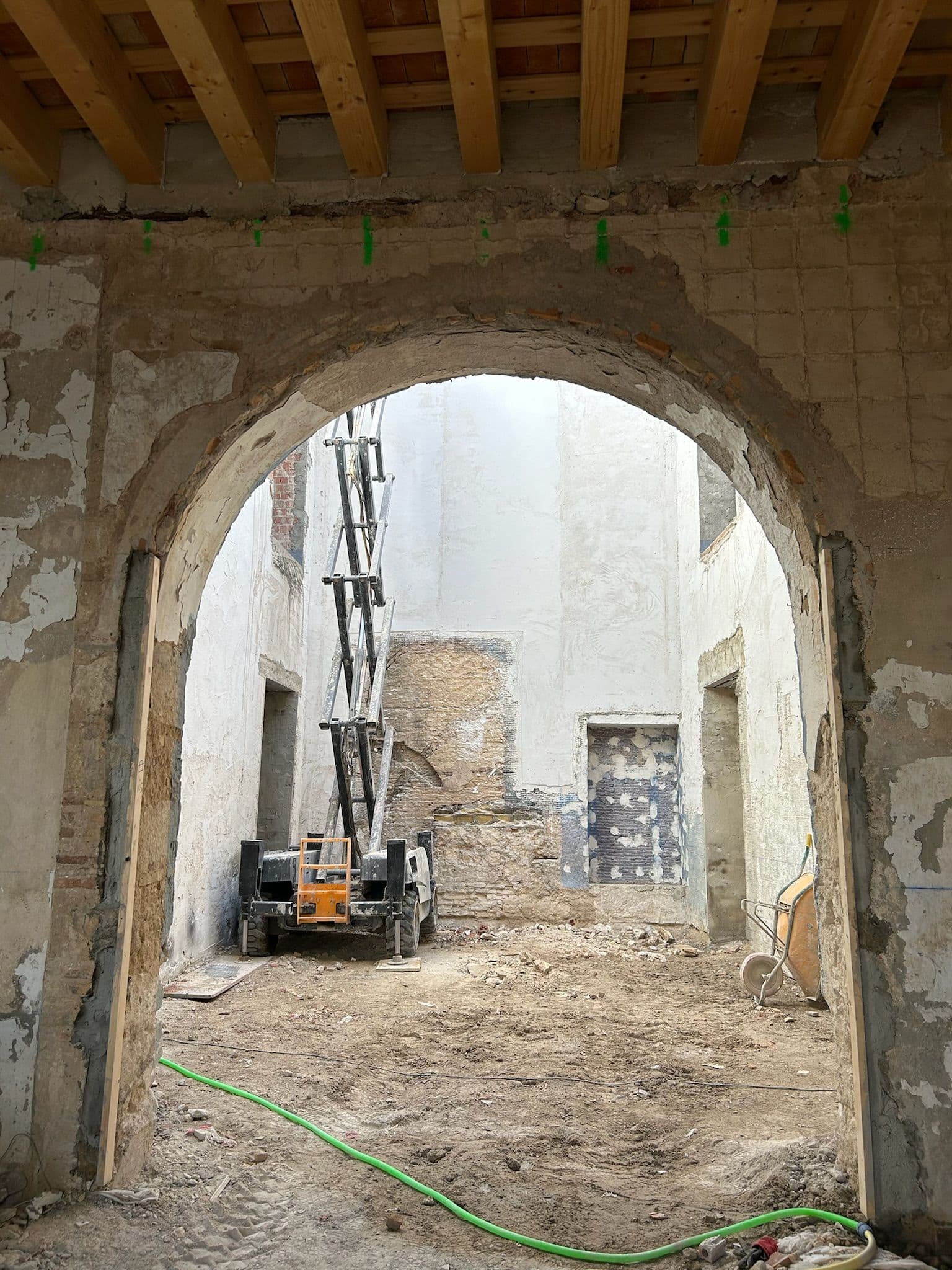 Arco de medio punto hacia el patio en obras, con techo de madera nueva