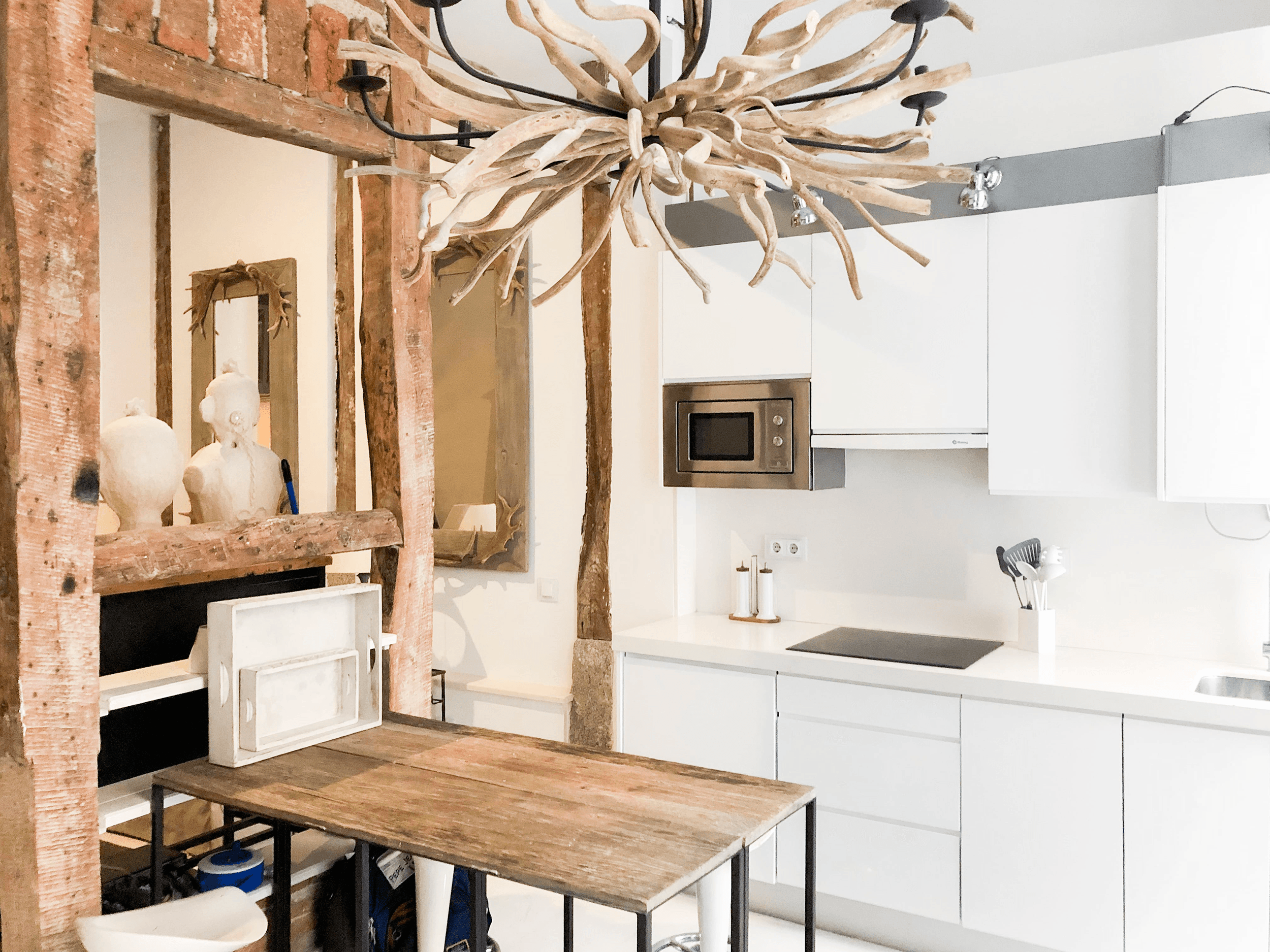 Cocina blanca con lámpara de cornamenta y mesa de trabajo de madera