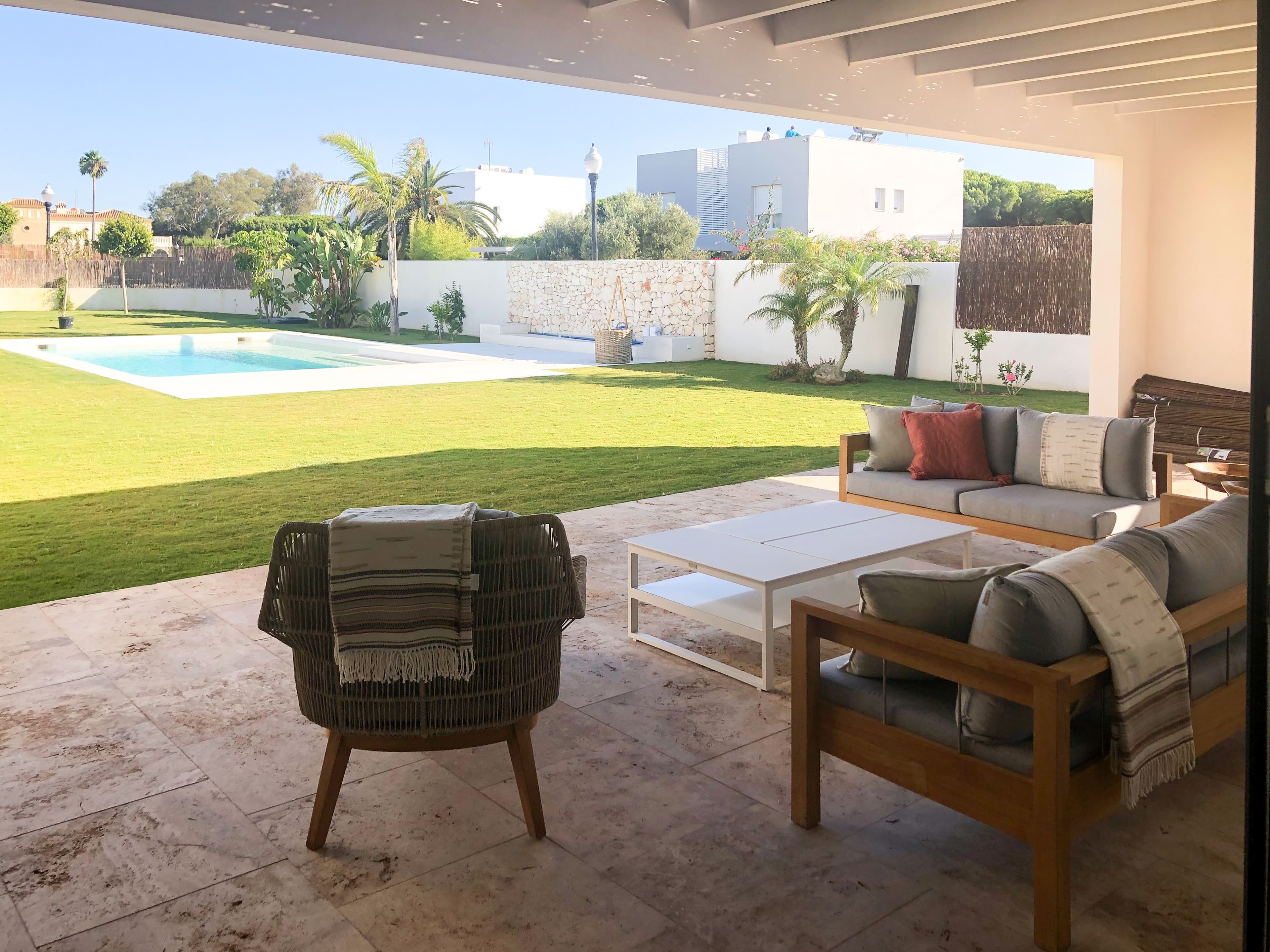 Porche con sofás de teca y vistas al césped y la piscina