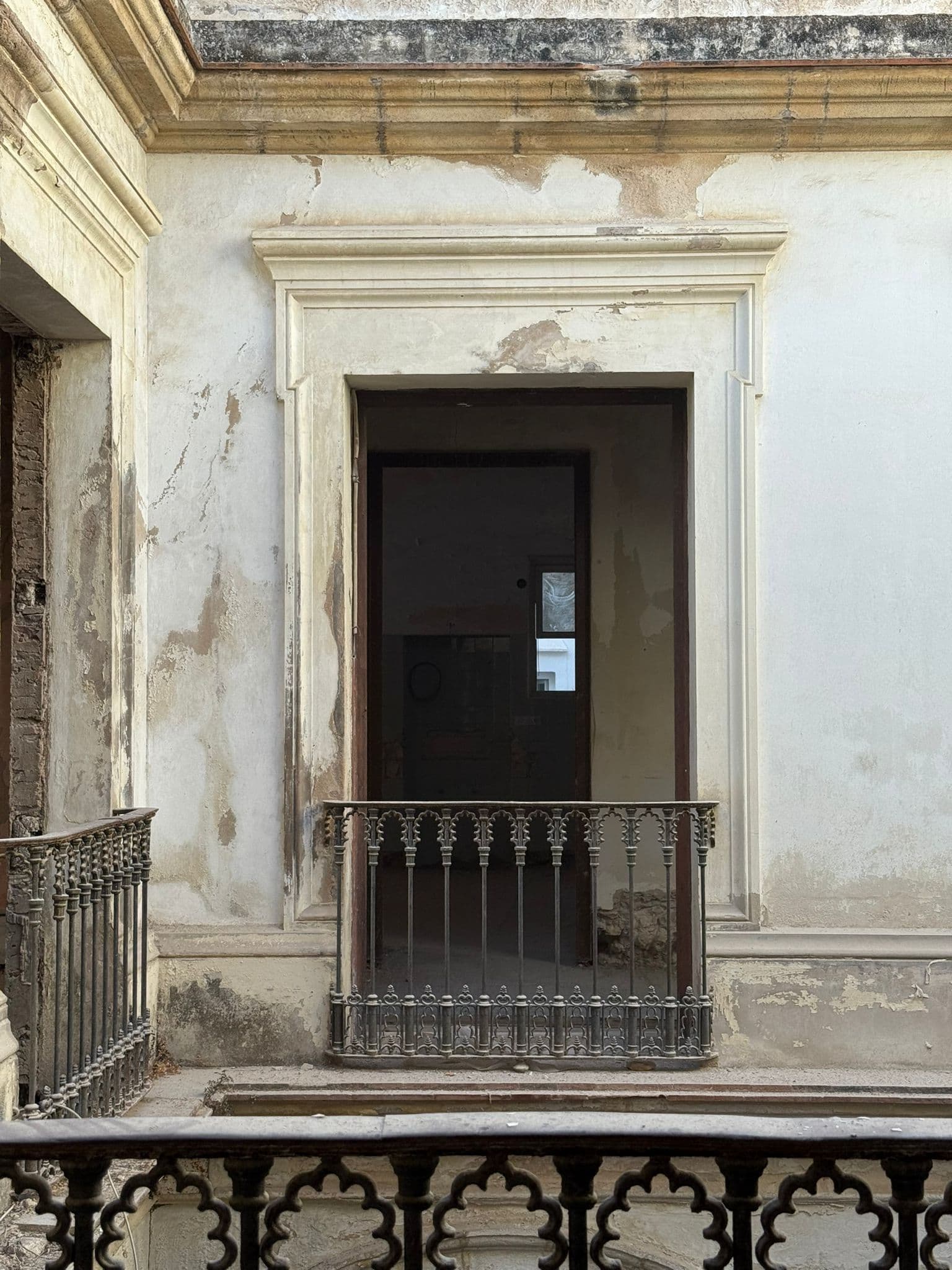 Puerta noble con recercado de piedra y balcón de hierro en el patio