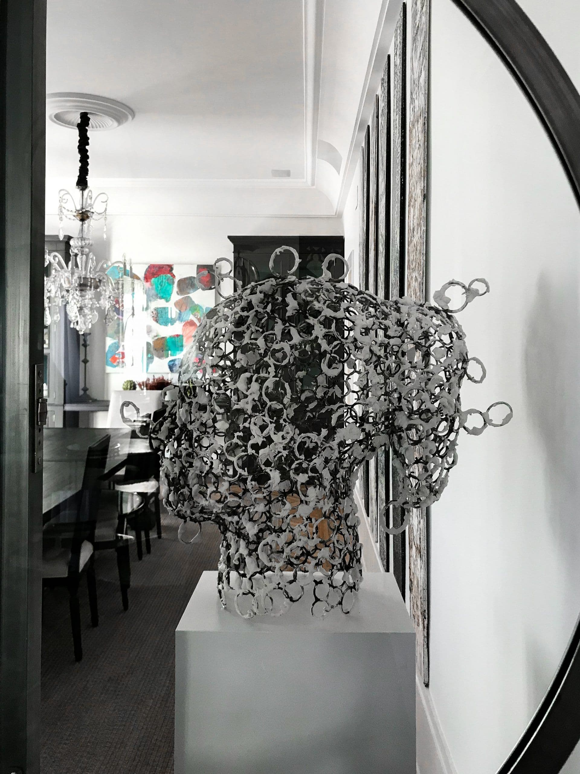Escultura de cabeza en filigrana metálica frente al comedor de espejos