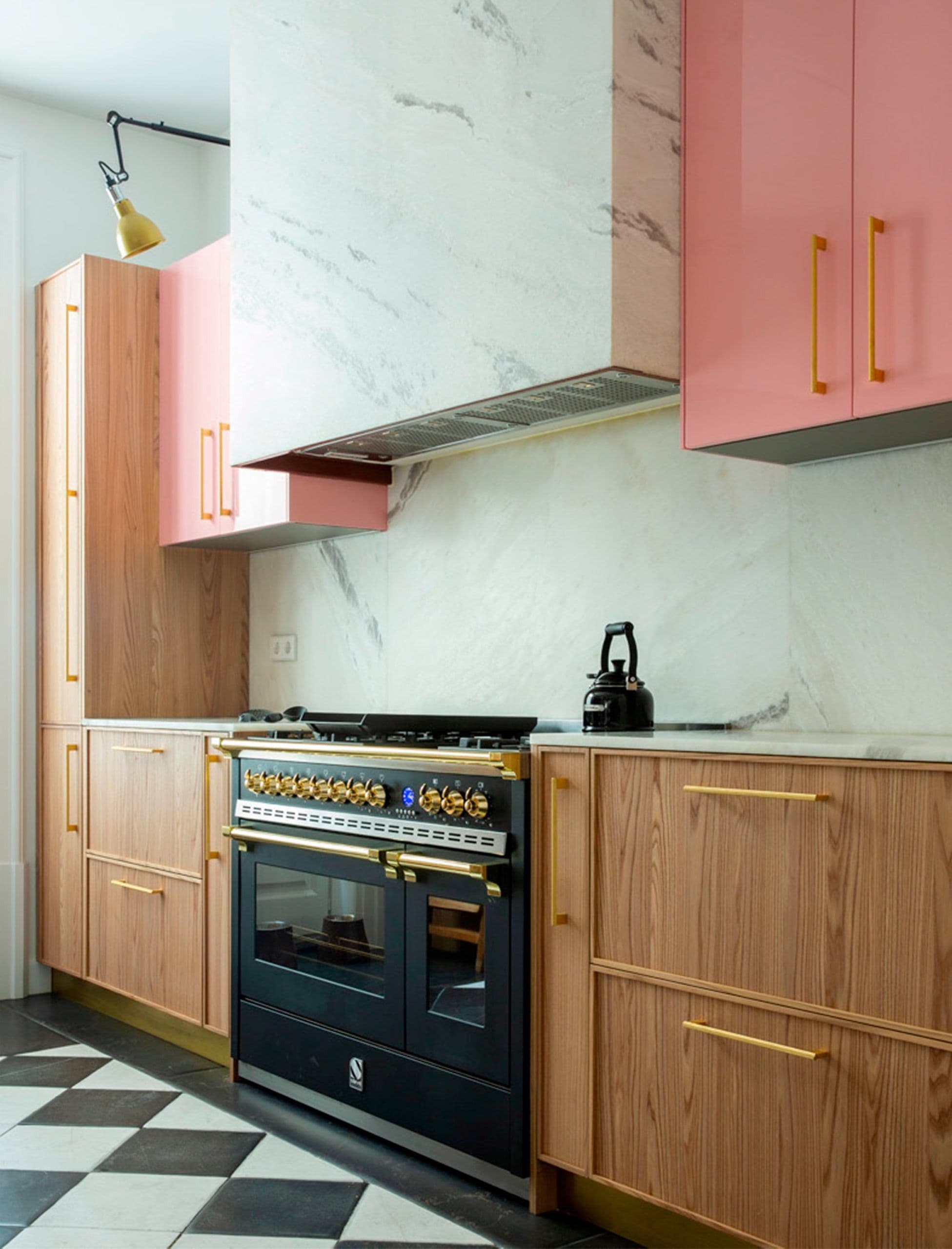 Cocina con muebles rosa empolvado y madera, campana de mármol y cocina negra de hierro