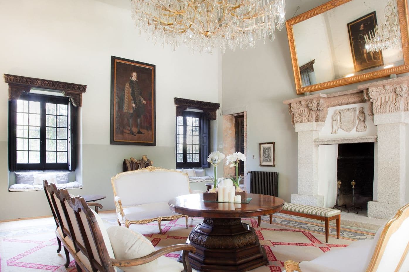 Salón clásico con chimenea, lámpara de araña y pareja de retratos antiguos