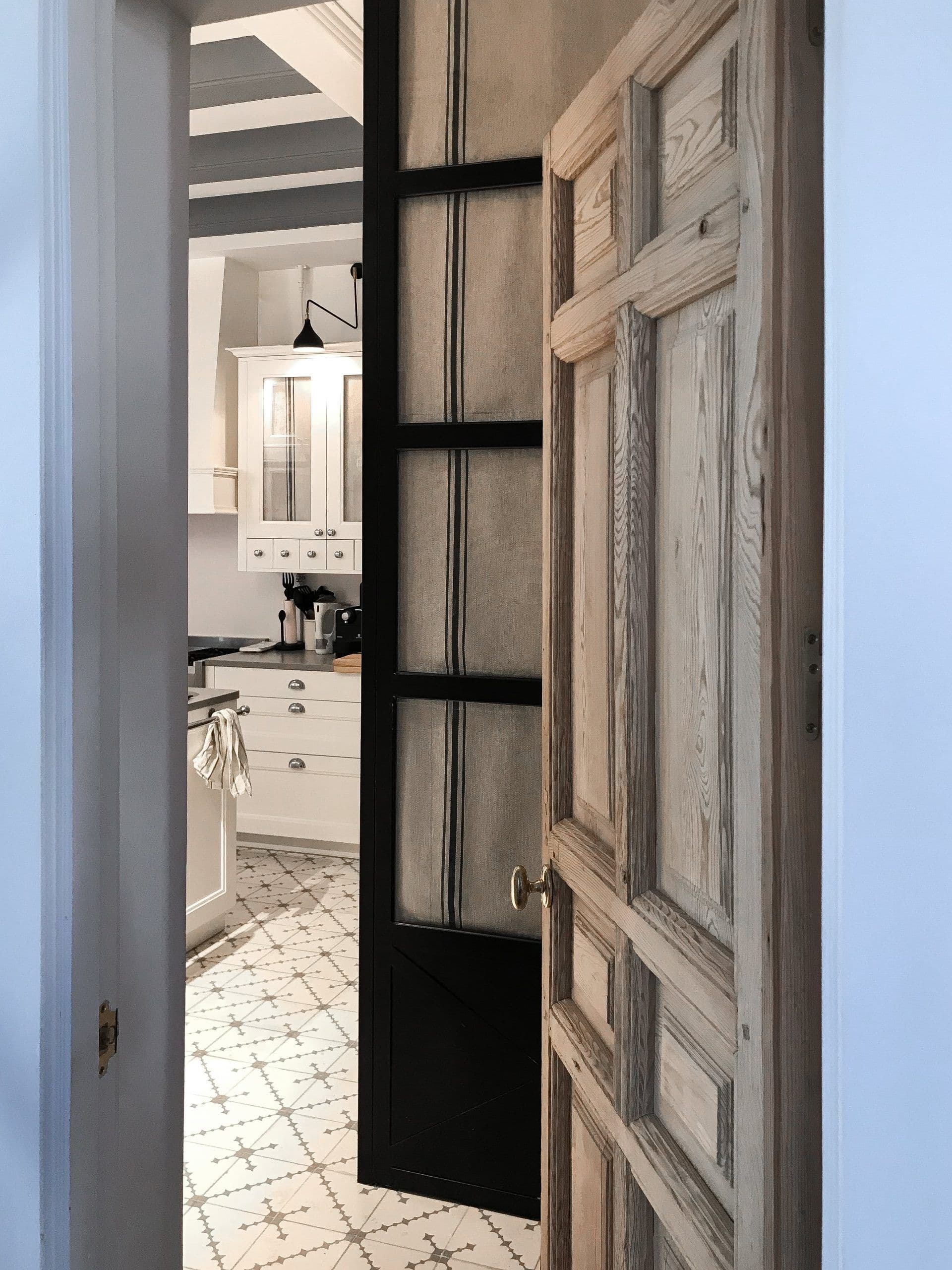 Puertas correderas de madera decapada abiertas a la cocina de baldosa hidráulica