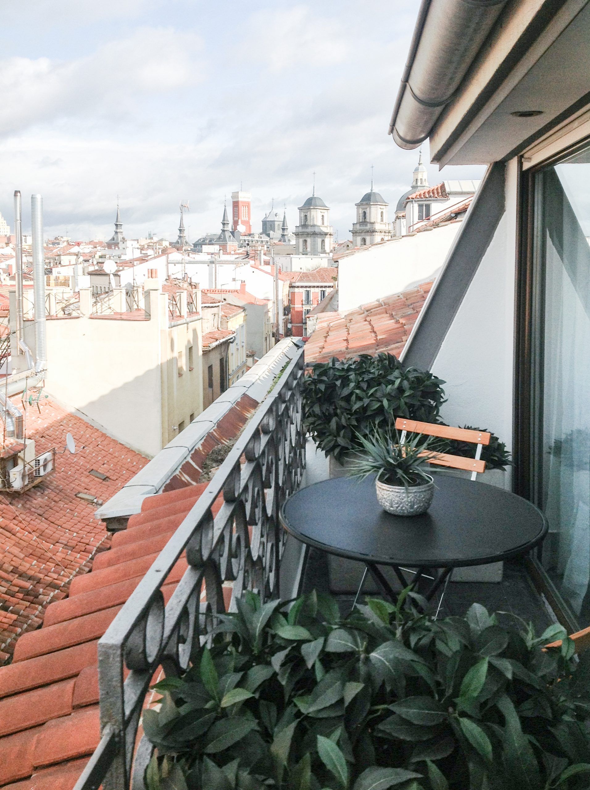 Terraza de ático con mesa de bistró sobre los tejados y cúpulas de Madrid
