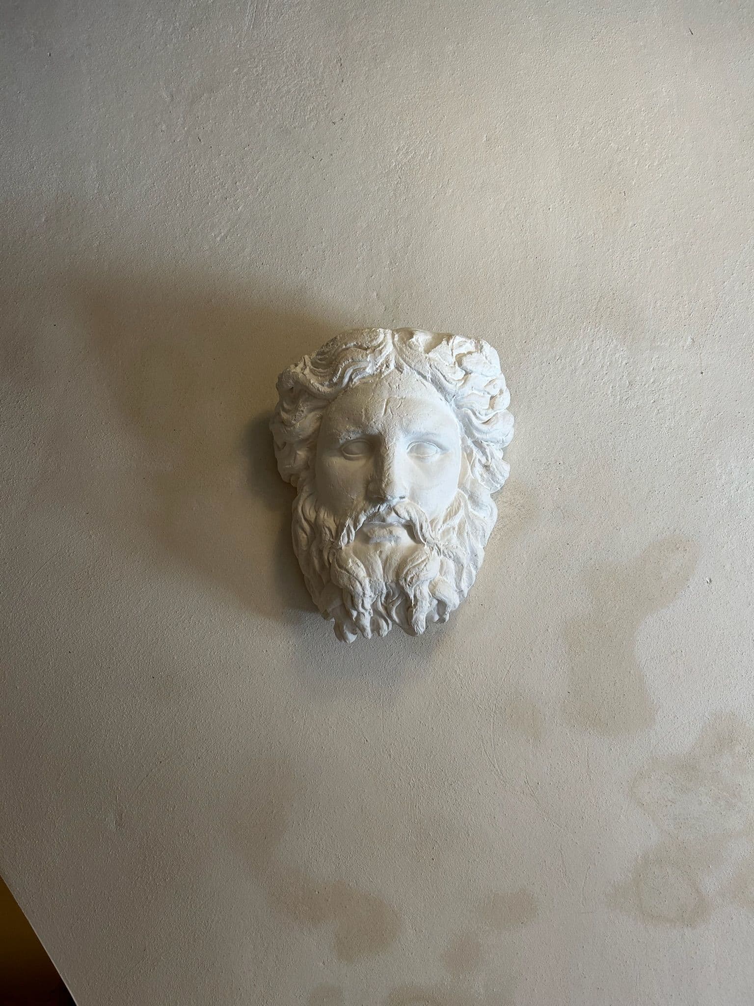 Mascarón de león en yeso sobre muro de cal