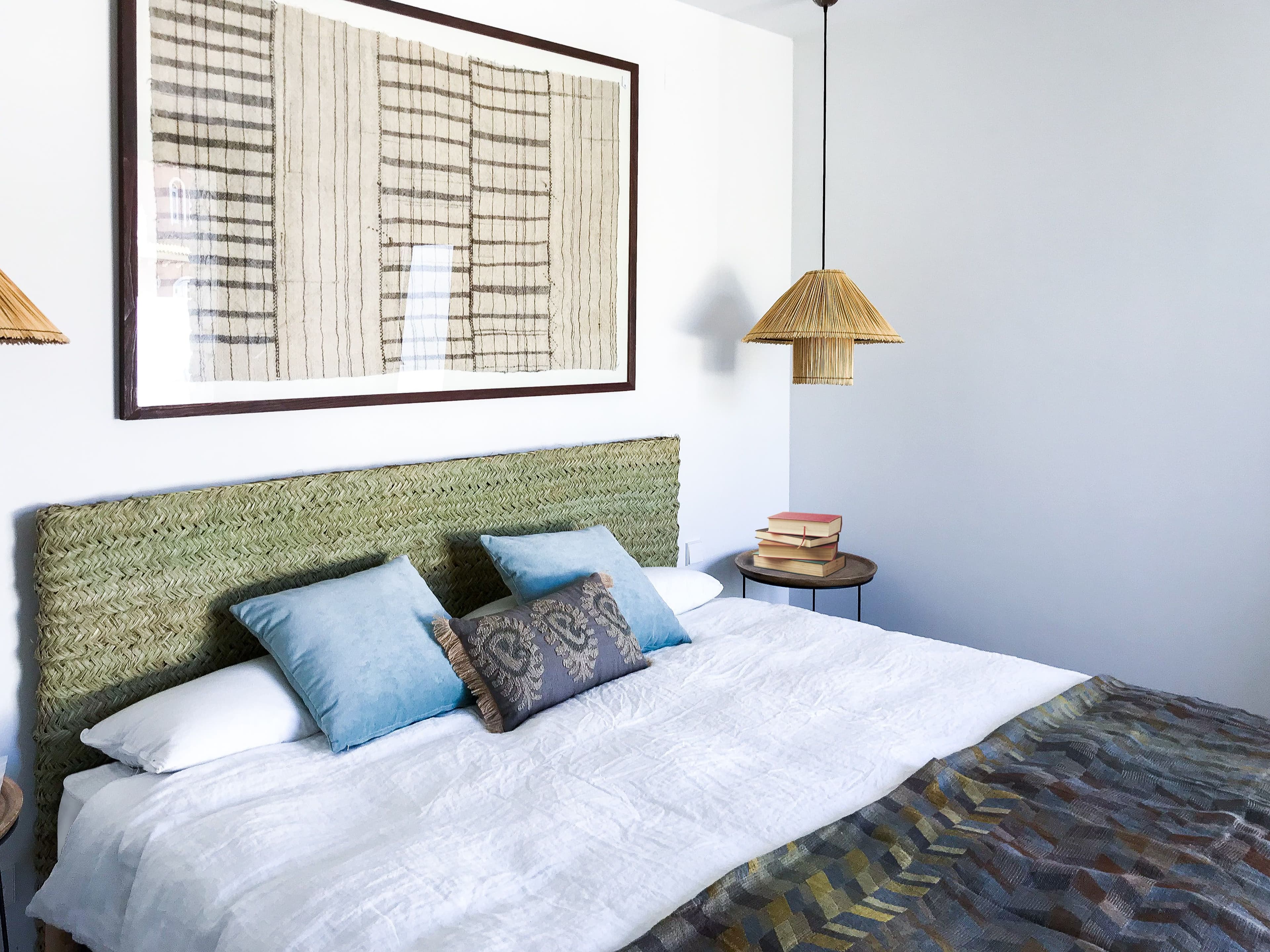 Dormitorio con cabecero tapizado en verde y textiles ikat