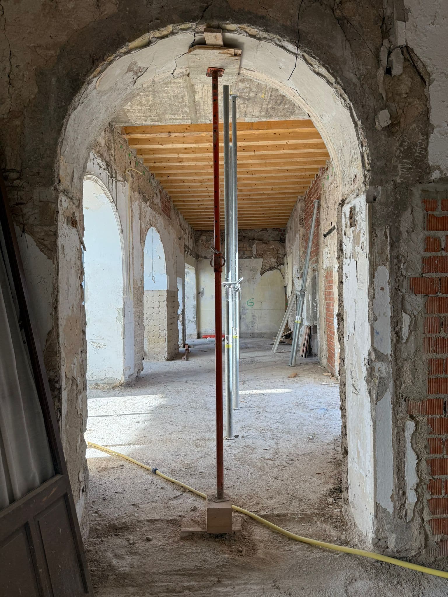 Nave de arcos apuntalada durante la rehabilitación, con ladrillo y cal vistos